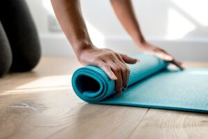 pilatesperfect photo shows a girl unrolling a Pilates mat in a class to imrpove fundamental core stability